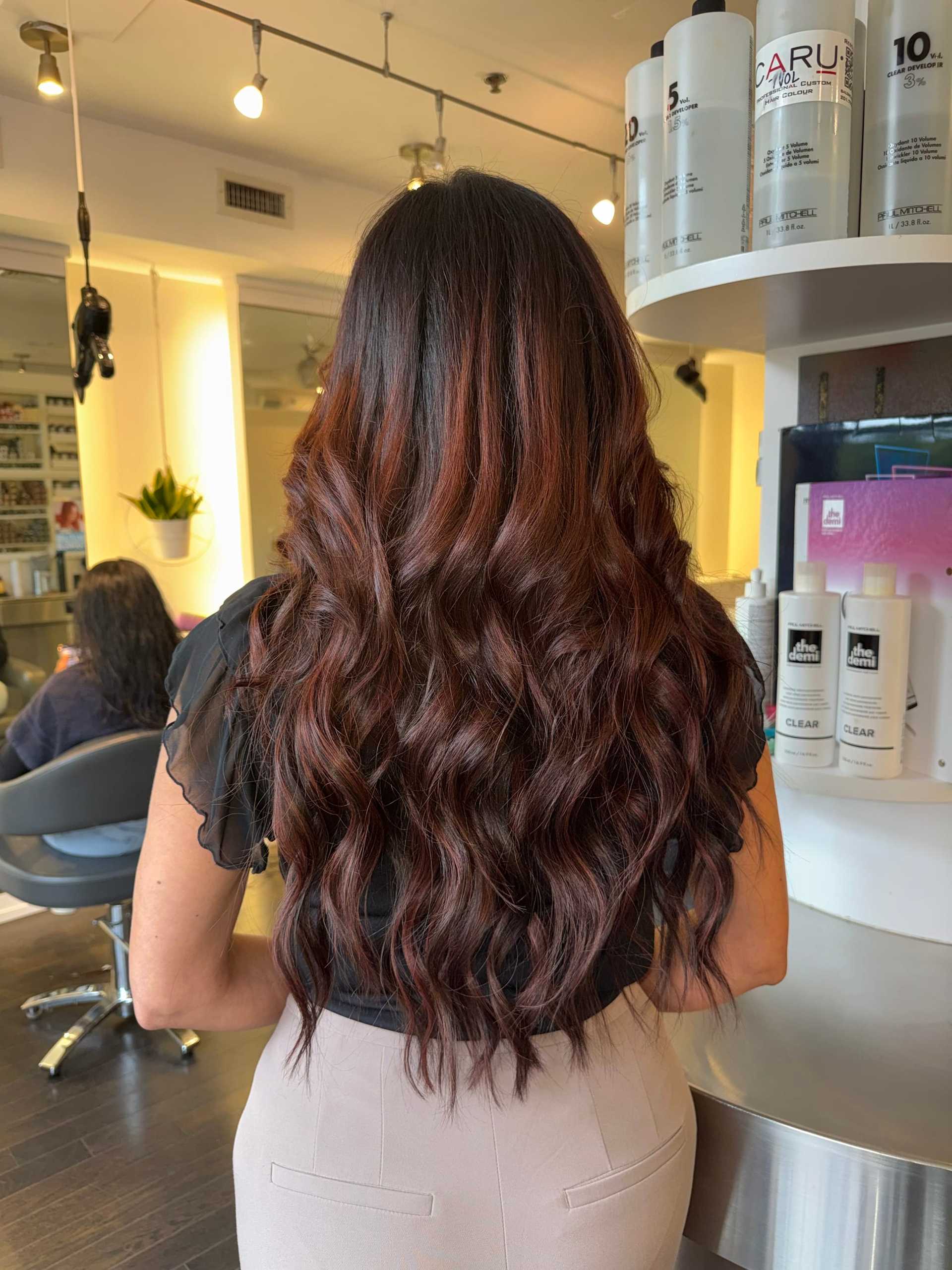 Long, dark auburn hair in loose waves at a salon.
