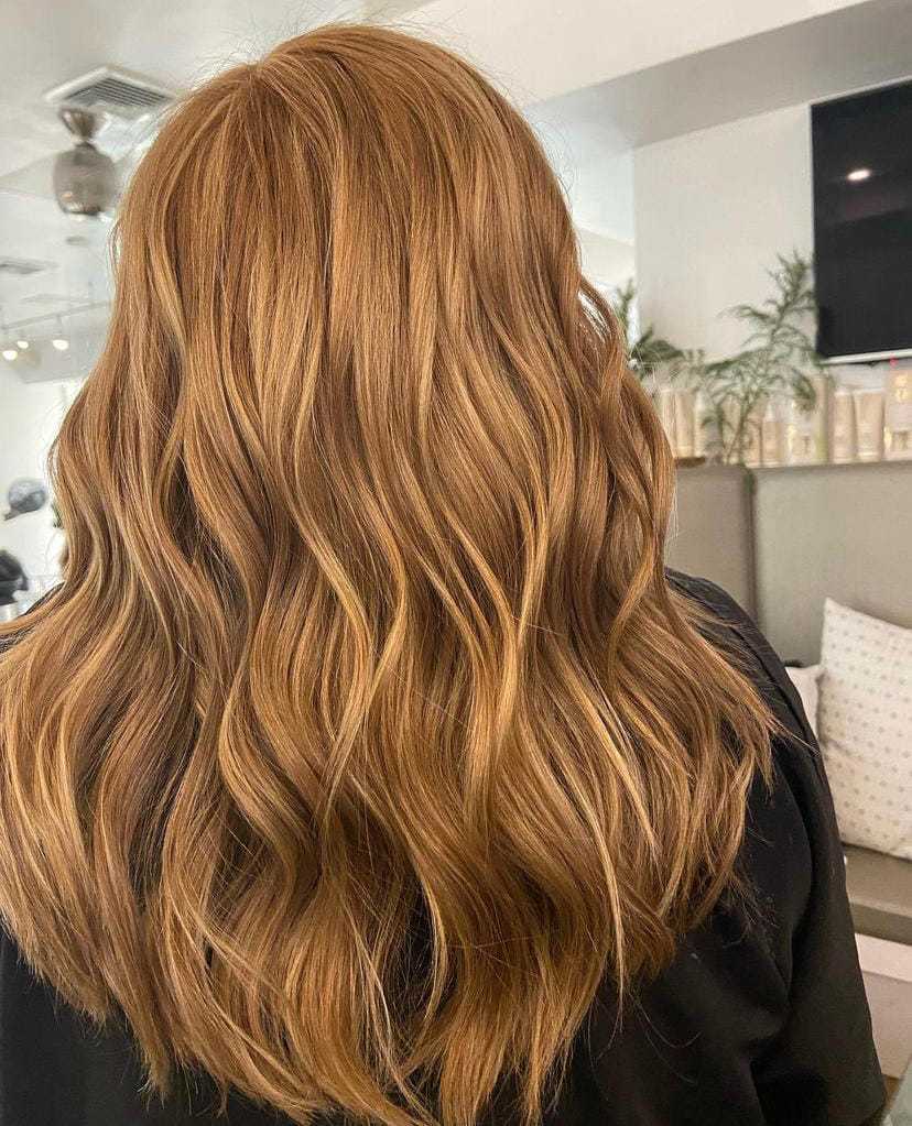Wavy copper hair styled with soft curls in a modern salon setting.