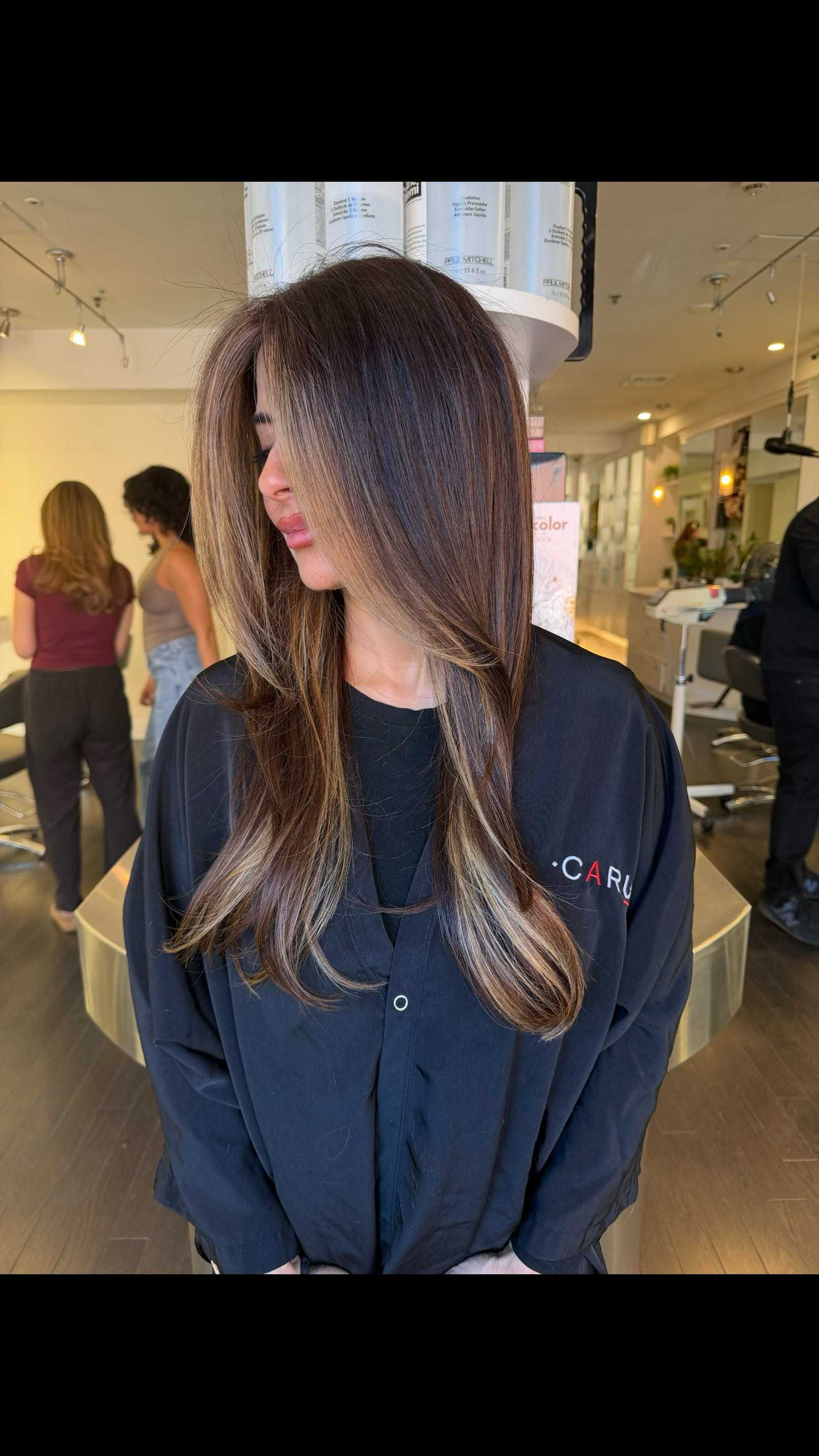 Woman with long, straight hair and subtle highlights in a salon.